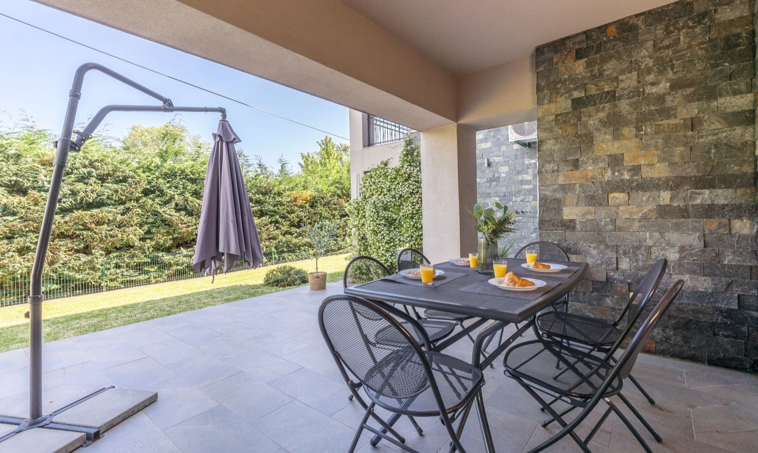 Apartment 3 terrace with parasol beside the stone wall